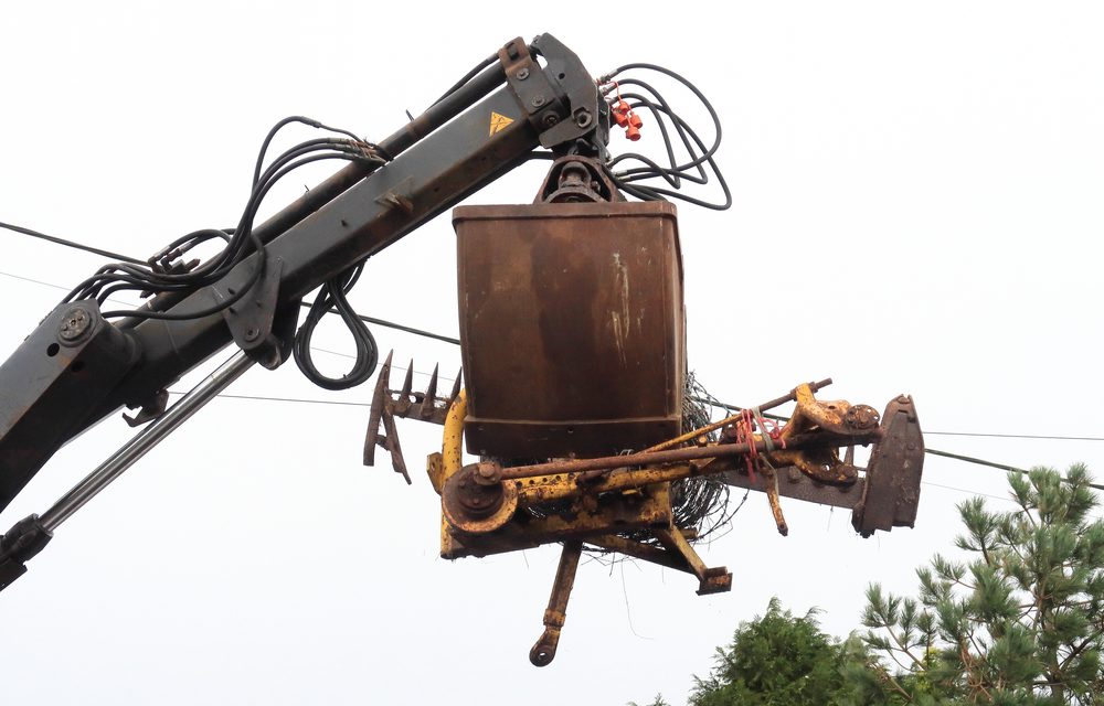 Grab hire lorry lifting some old machinery with its jaws